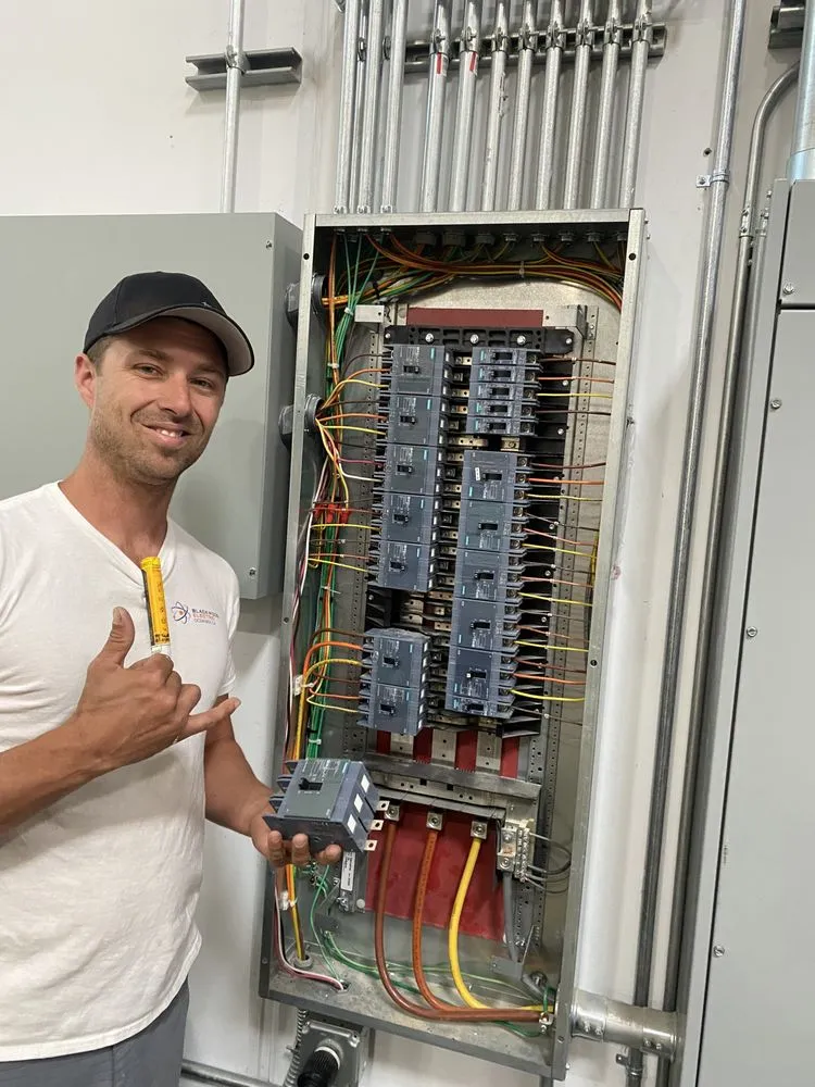 Travis Tompkins beside a large commercial panel he wired